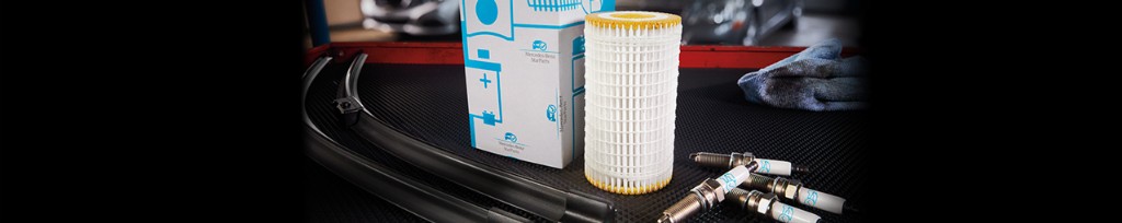 Mercedes-Benz StarParts packaging with oil filter, wiper blades and spark plugs on a workshop surface